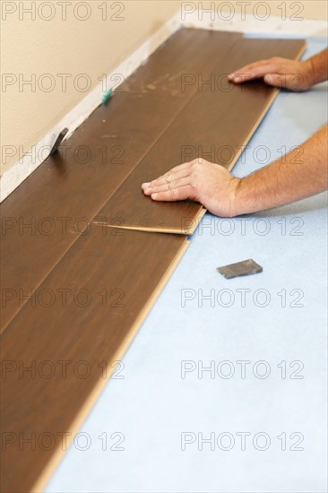 Man installing new laminate wood flooring abstract