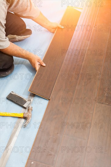 Man installing new laminate wood flooring abstract