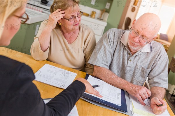 Senior adult couple going over documents in their home with agent at signing