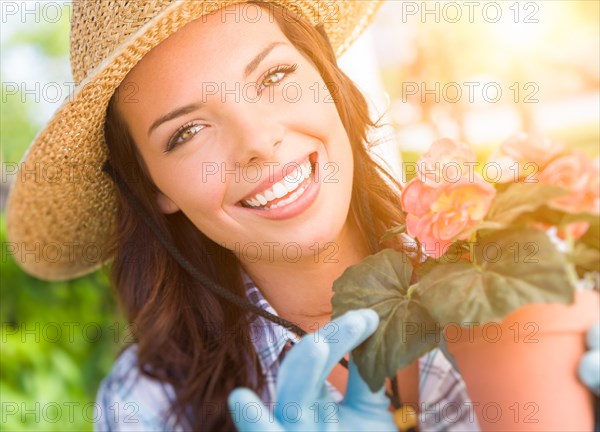 Happy young adult woman wearing hat and gloves gardening outdoors