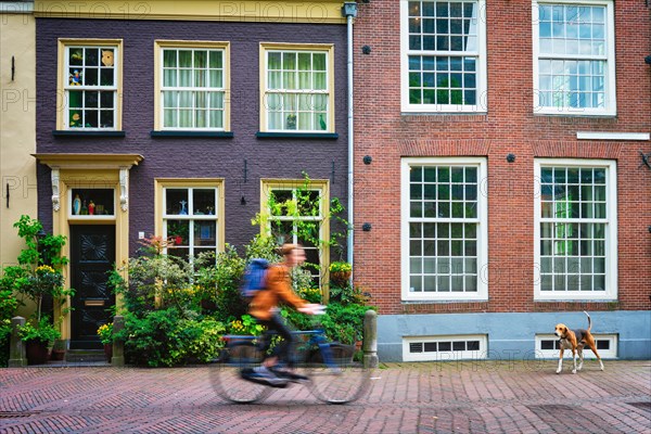 Motion blurred bicycle rider cyclist man on bicycle very popular means of transport in Netherlands in street with old houses of Delft