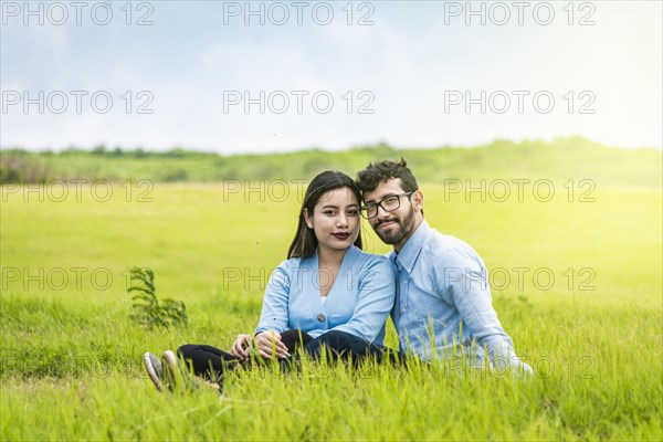 Portrait of a couple in love sitting on the grass in the field