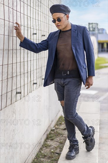 Latin gay male with makeup wearing fashion hat doing catwalk in the street
