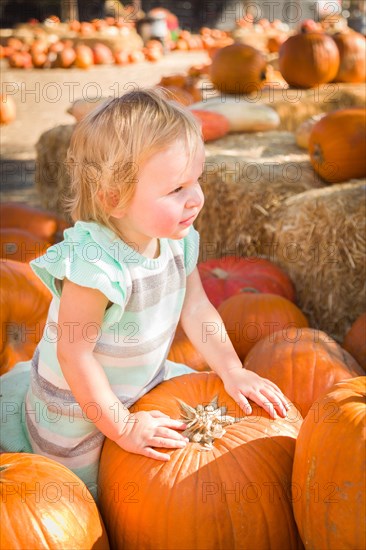 Adorable baby girl having fun in a rustic ranch setting at the pumpkin patch