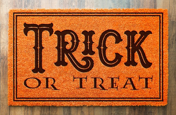 Trick or treat halloween orange welcome mat on wood floor background