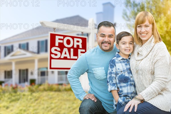 Happy mixed-race hispanic and caucasian family portrait in front of house and sold for sale real estate sign