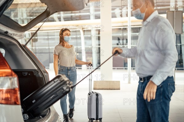 Thinking traveling woman waiting for her luggage being taken out from the taxi or Uber car trunk