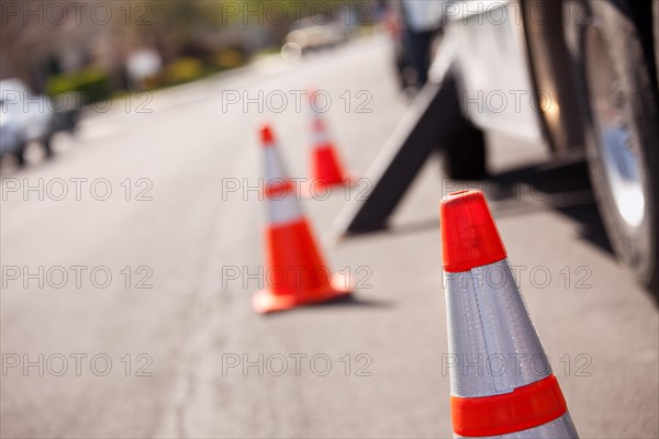 Several orange hazard cones and utility truck in street