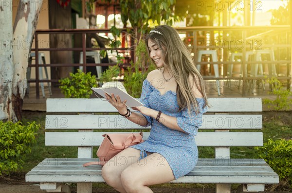 A cute girl sitting on a bench reading a book