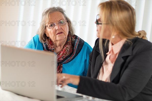 Woman helping senior adult lady on laptop computer
