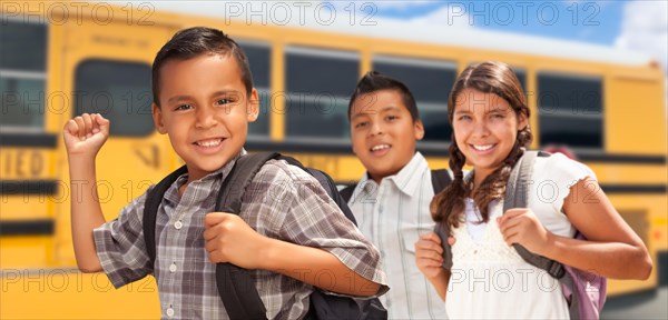 Young hispanic boys and girl walking near school bus