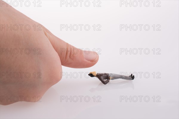 Hand threatening to smash human figure on a white background