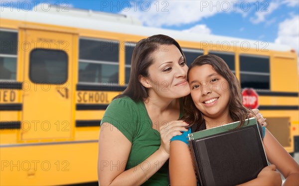 Hispanic mother and daughter near school bus