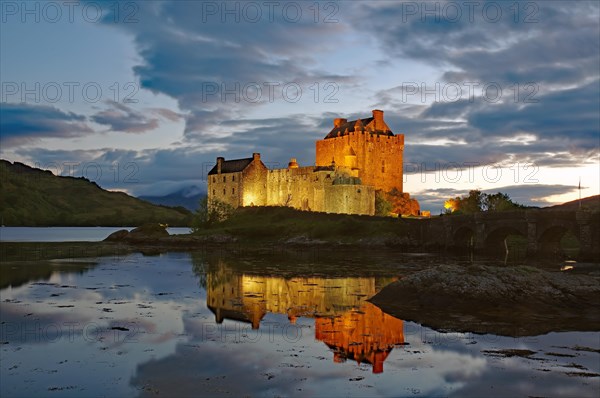 Das angestrahlte Castle Eilean Donan spiegelt sich im Wasser des Loch