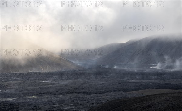 Steaming lava fields between hills