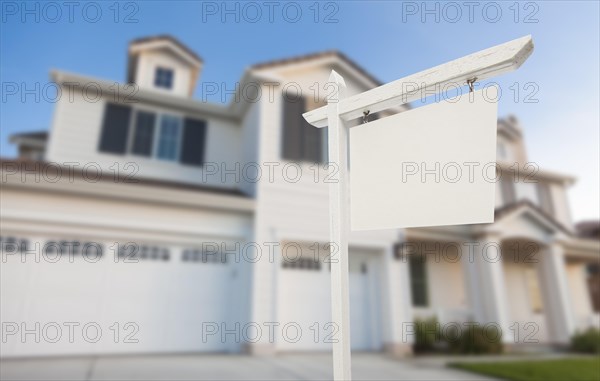 Blank real estate sign in front of beautiful new house