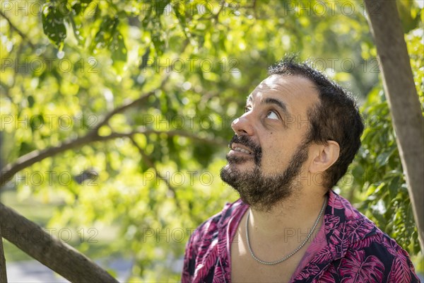 Bearded mature man wearing a fuchsia shirt with blurred green background