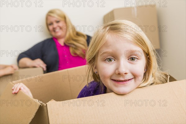 Happy young mother and daughter having fun with moving boxes