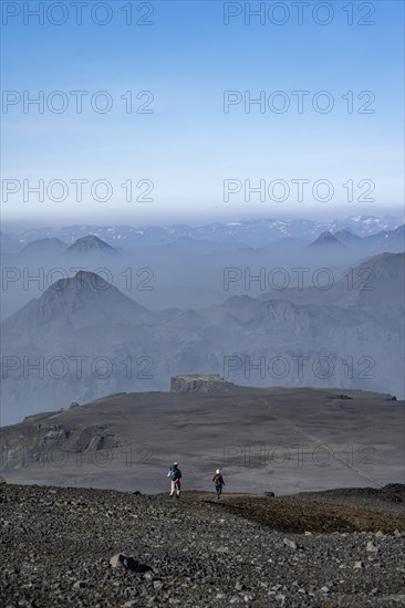 Two hikers on trail through volcanic landscape