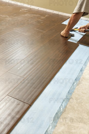 Man installing new laminate wood flooring abstract