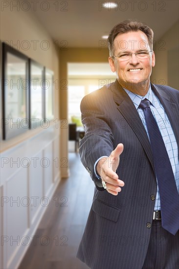 Smiling male agent reaching for hand shake in hallway of beautiful new house