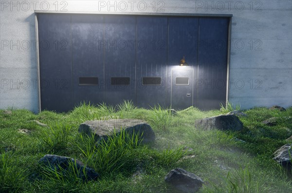 Mysterious cement wall and iron door with windows surrounded by large frame and big stones and grass in front