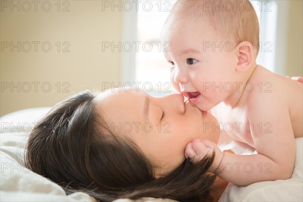 Young mixed-race chinese and caucasian baby boy laying in his bed with his mother