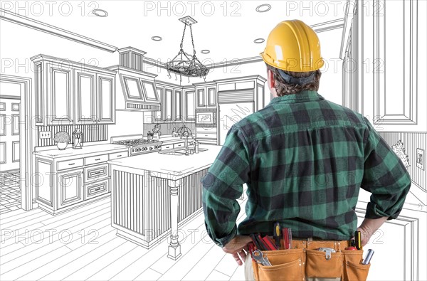 Male contractor with hard hat and tool belt looking at custom kitchen drawing on white