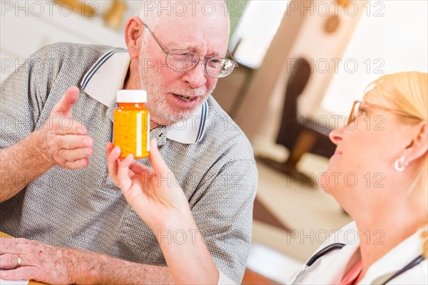 Doctor or nurse explaining prescription medicine to attentive senior man
