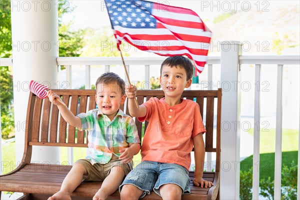 Young mixed-race chinese and caucasian brothers playing with american flags