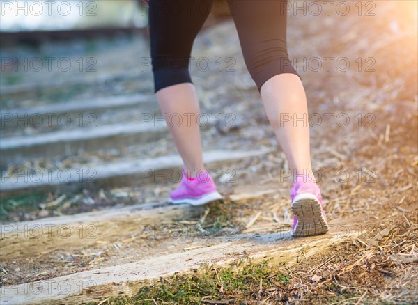 Young fit adult woman outdoors walking or running up wooden steps