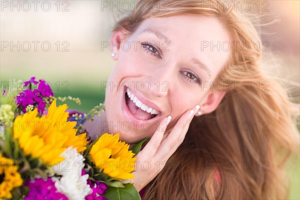 Outdoor portrait of an excited young adult brown eyed woman holding a bouquet of flowers