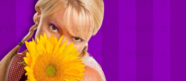 Beautiful girl holding yellow sunflower against purple striped background