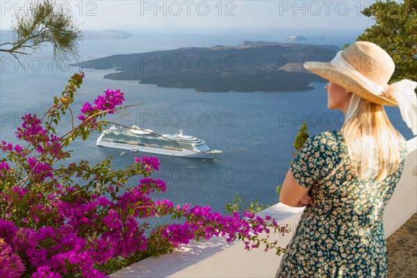 Attractive female tourist admiring the view of the cruise ship off the coast of santorini Greece