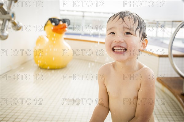 mixed-race boy having fun at the water park with large rubber duck in the background