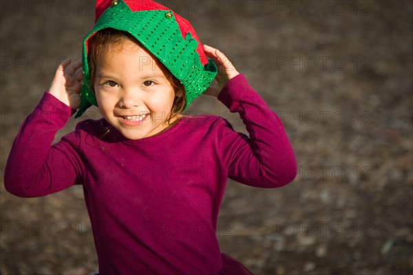 Cute mixed-race young baby girl having fun wearing christmas hat outdoors