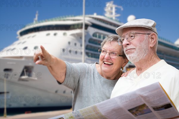 Happy senior adult couple tourists with brochure next to passenger cruise ship