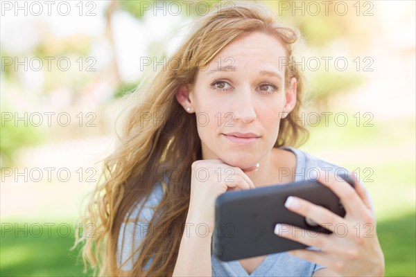 Concerned young woman outdoors looking at her smart phone