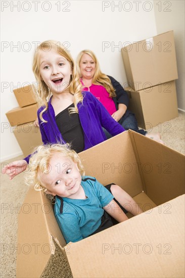 Playful young family in empty room playing with moving boxes