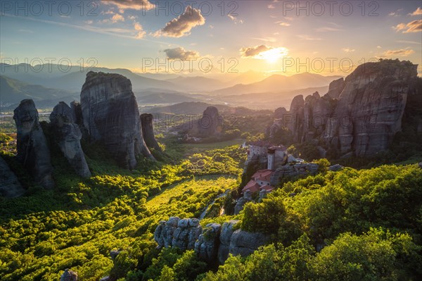 Sunset over monastery of Rousanou and Monastery of St. Nicholas Anapavsa in famous greek tourist destination Meteora in Greece on sunset with sun rays and lens flare