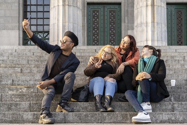 Multi ethnic group of friends sitting on some stairs having a good time chatting