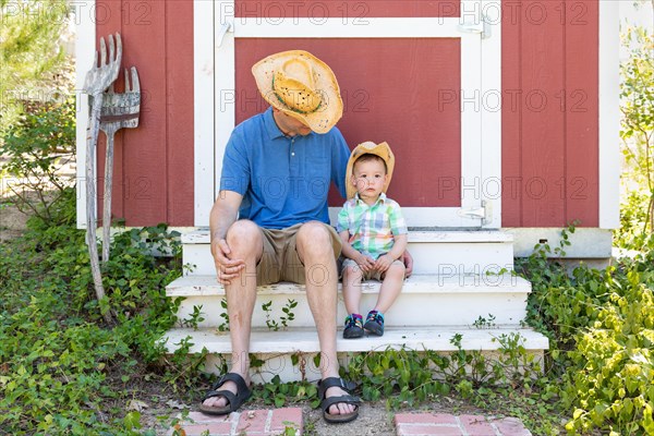 Playful young caucasian father and mixed-race chinese son wearing cowboy hats