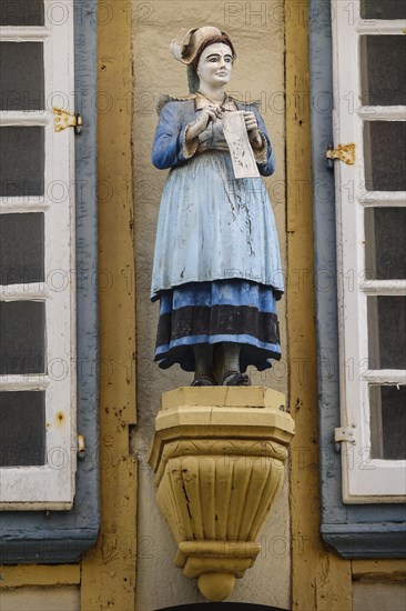 Half-timbered house of a pastry shop with statue of a woman in historical traditional costume in the Rue Kereon