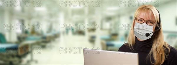 Woman sitting at computer with phone headset within hospital