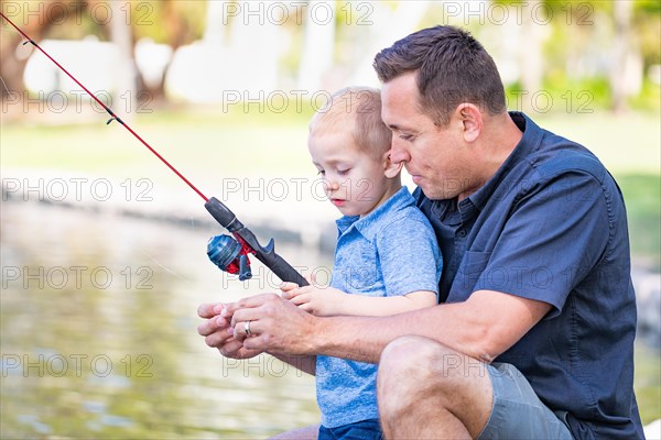 Young caucasian father and son having fun fishing at the lake