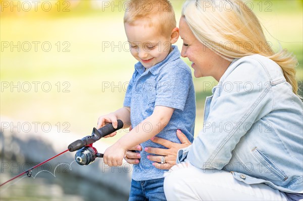 Young caucasian mother and son having fun fishing at the lake