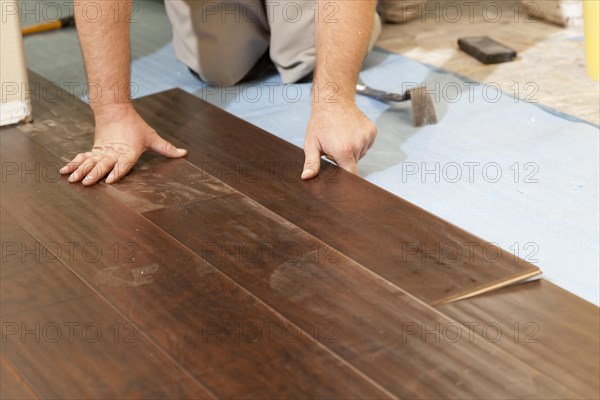 Man installing new laminate wood flooring abstract