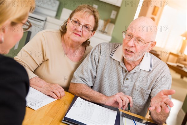 Senior adult couple going over documents in their home with agent at signing