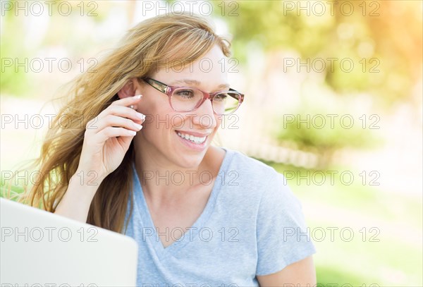 Young adult woman wearing glasses outdoors using her laptop