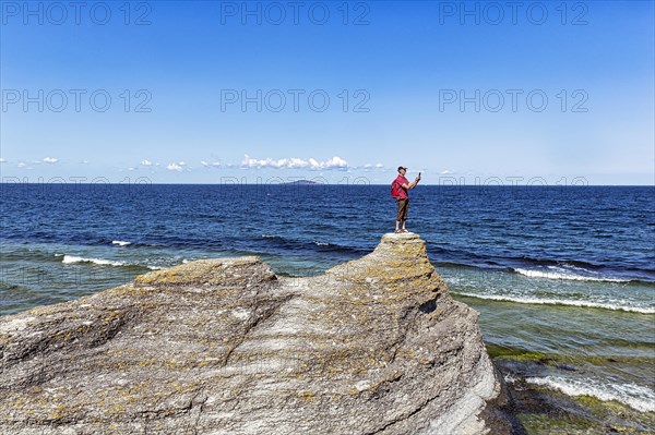 Hiker standing on limestone pillar photographing landscape